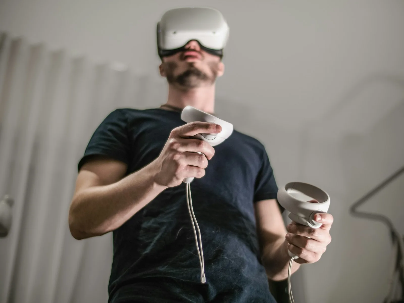 A man wearing a virtual reality headset holding a wii controller