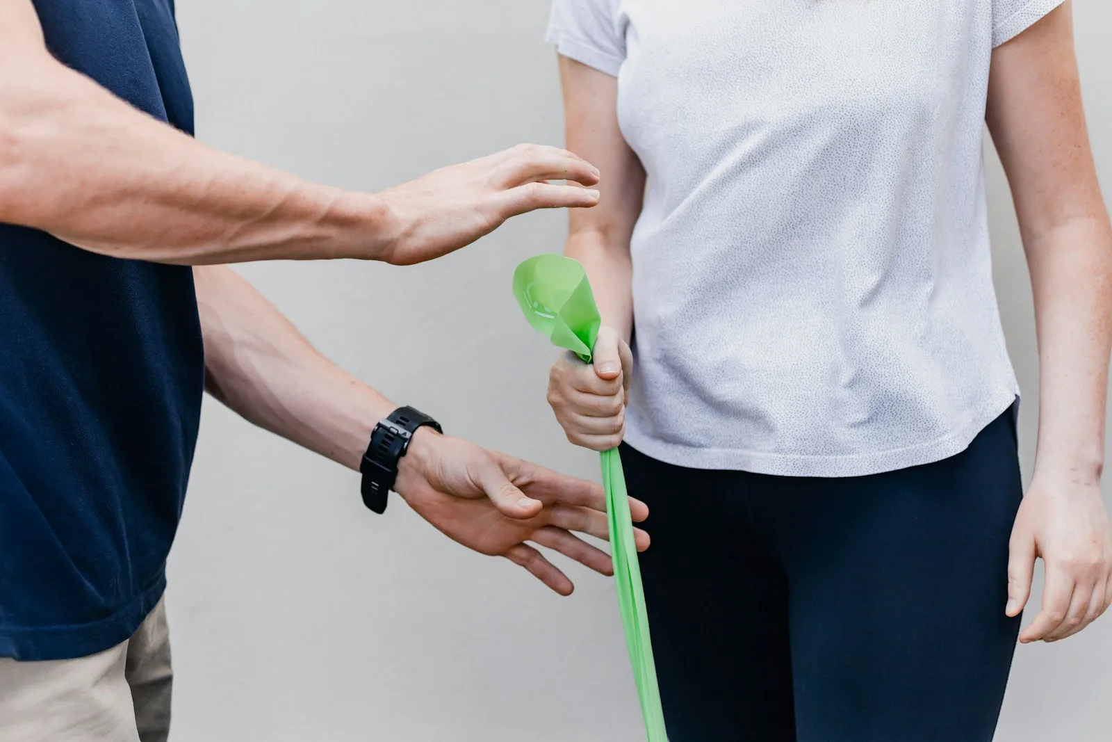 A person holding a small green object during a hand exercise