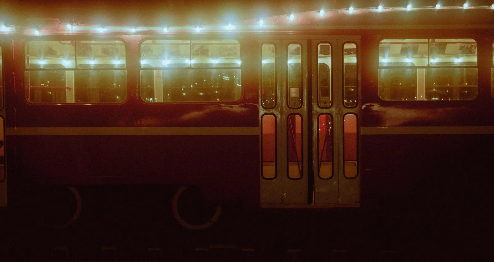 A train carriage at night with glowing windows and string lights